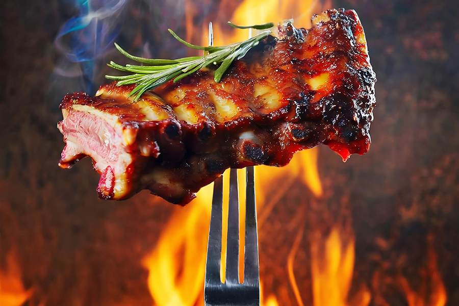 grilled beef ribs on the grill chopped on a fork against a fire